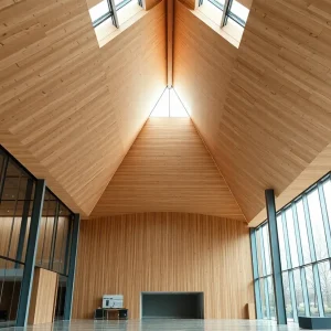 Interior of showroom with large triangular CLT wooden roof, glass facade and column‑free atrium